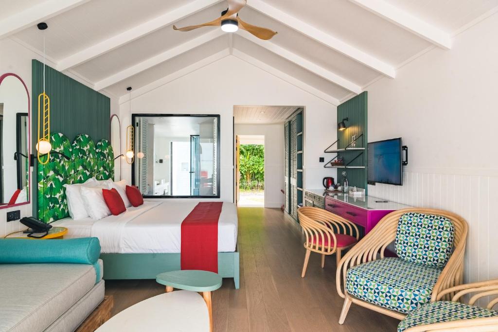 Bright resort guest villa interior with a dressed bed, rattan seating and open garden view